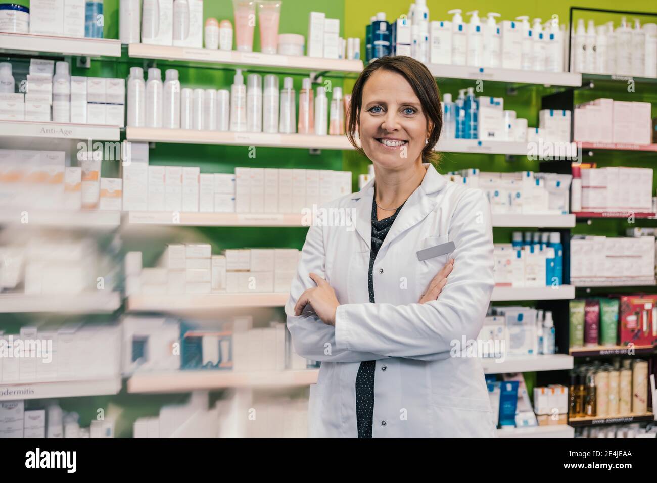 Confident pharmacist with arms crossed in chemist shop Stock Photo