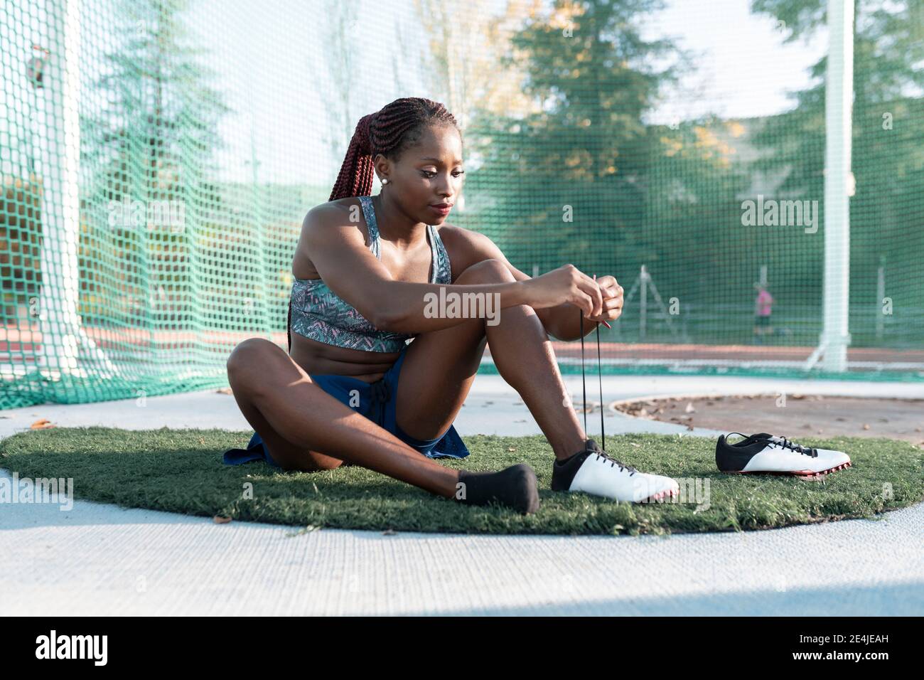Female athlete tying shoelace against net in sports court Stock Photo