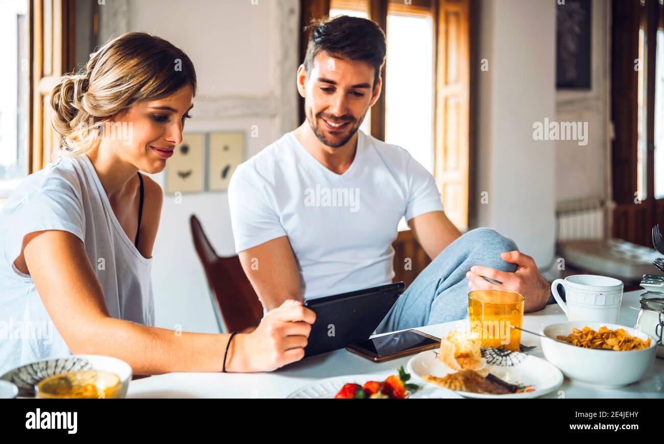 Young couple watching tablet while having breakfast at home Stock Photo