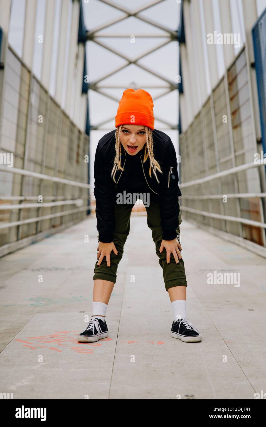 Young woman with mouth open bending while standing on footbridge Stock Photo