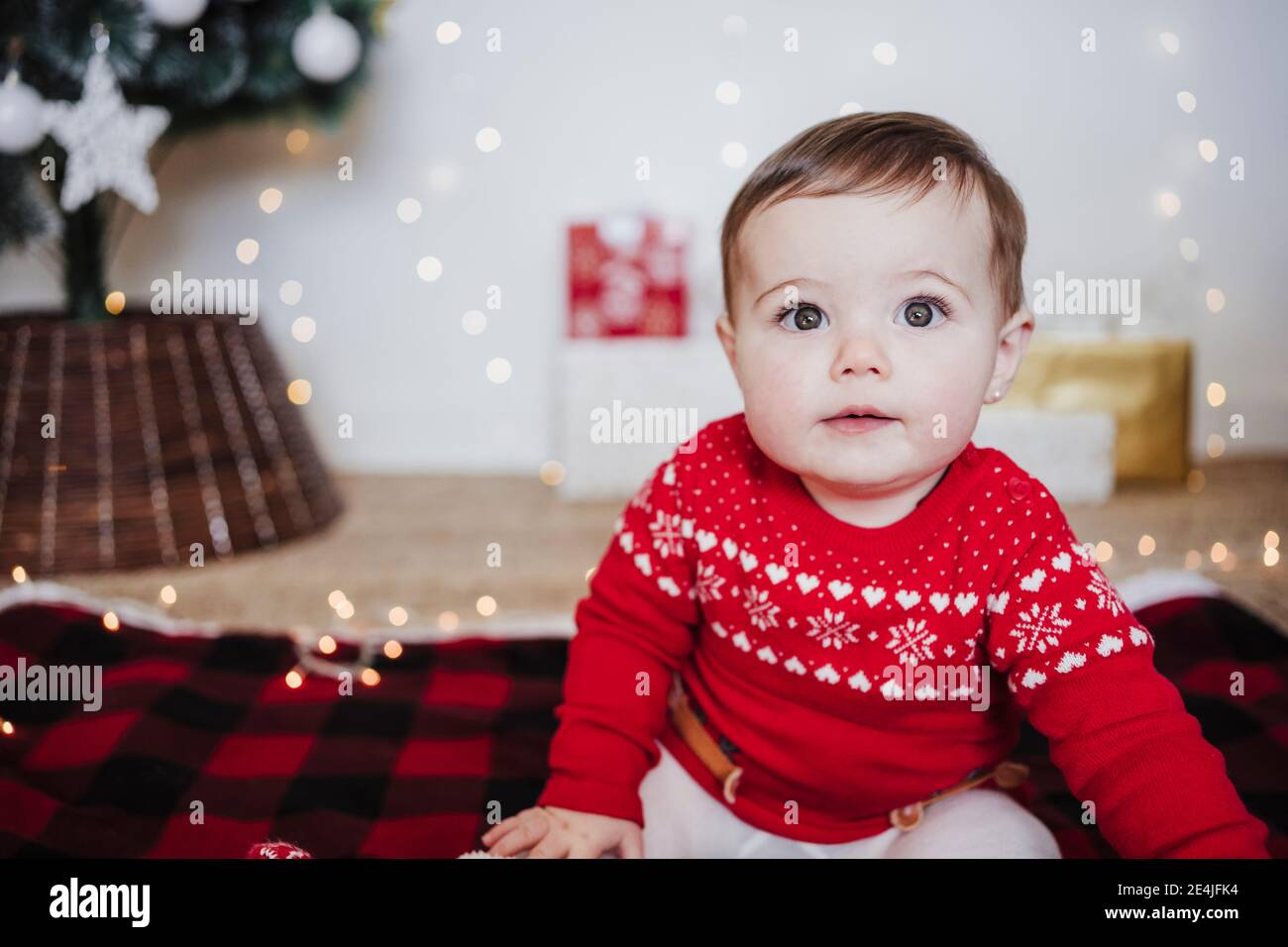 Cute baby girl staring while sitting at home during Christmas Stock Photo