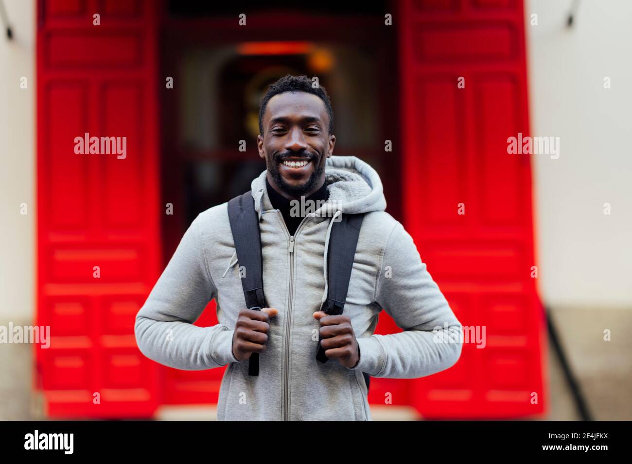 Young man carrying backpack while standing outdoors Stock Photo