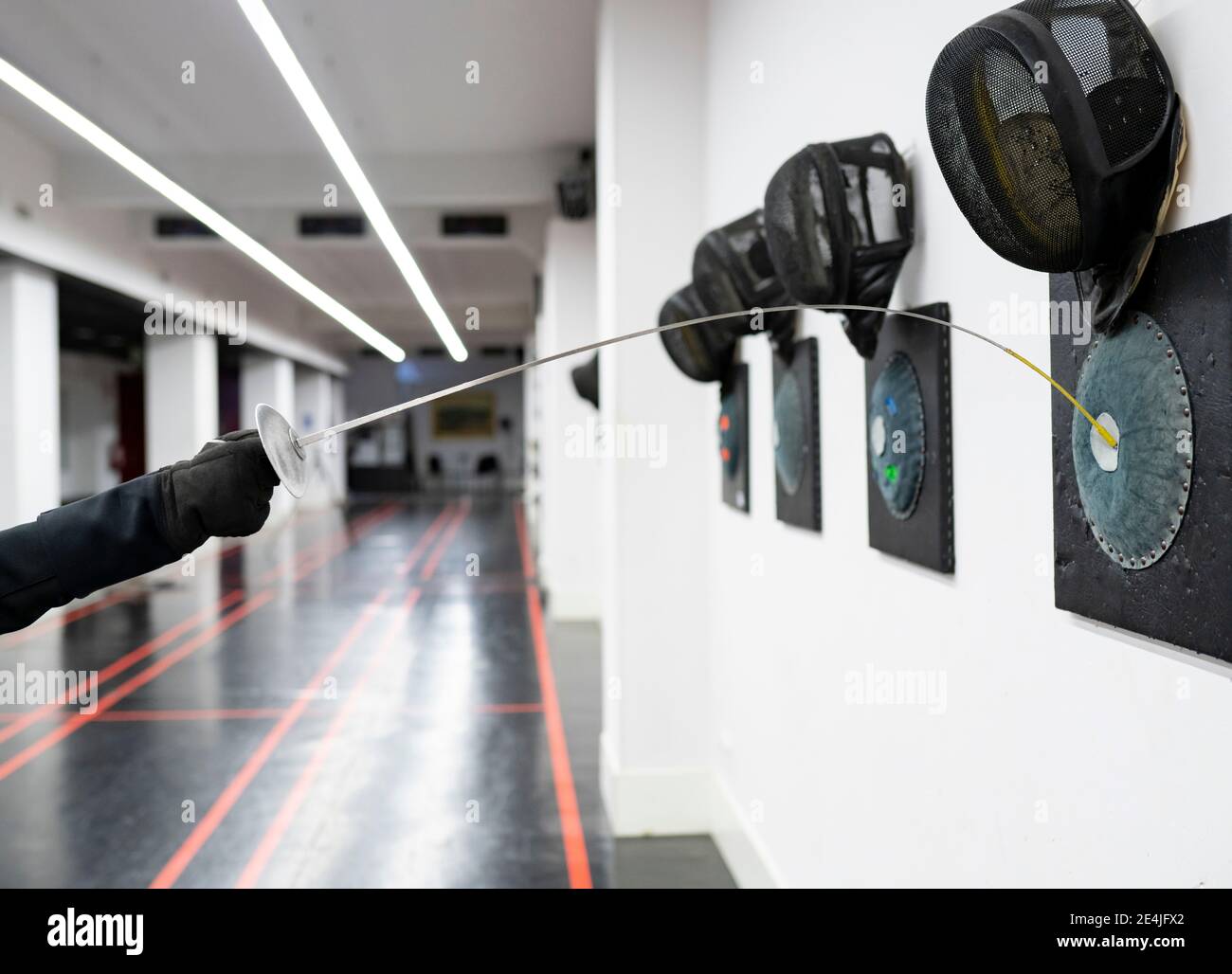 Woman's hand with fencing sword hitting target at gym Stock Photo