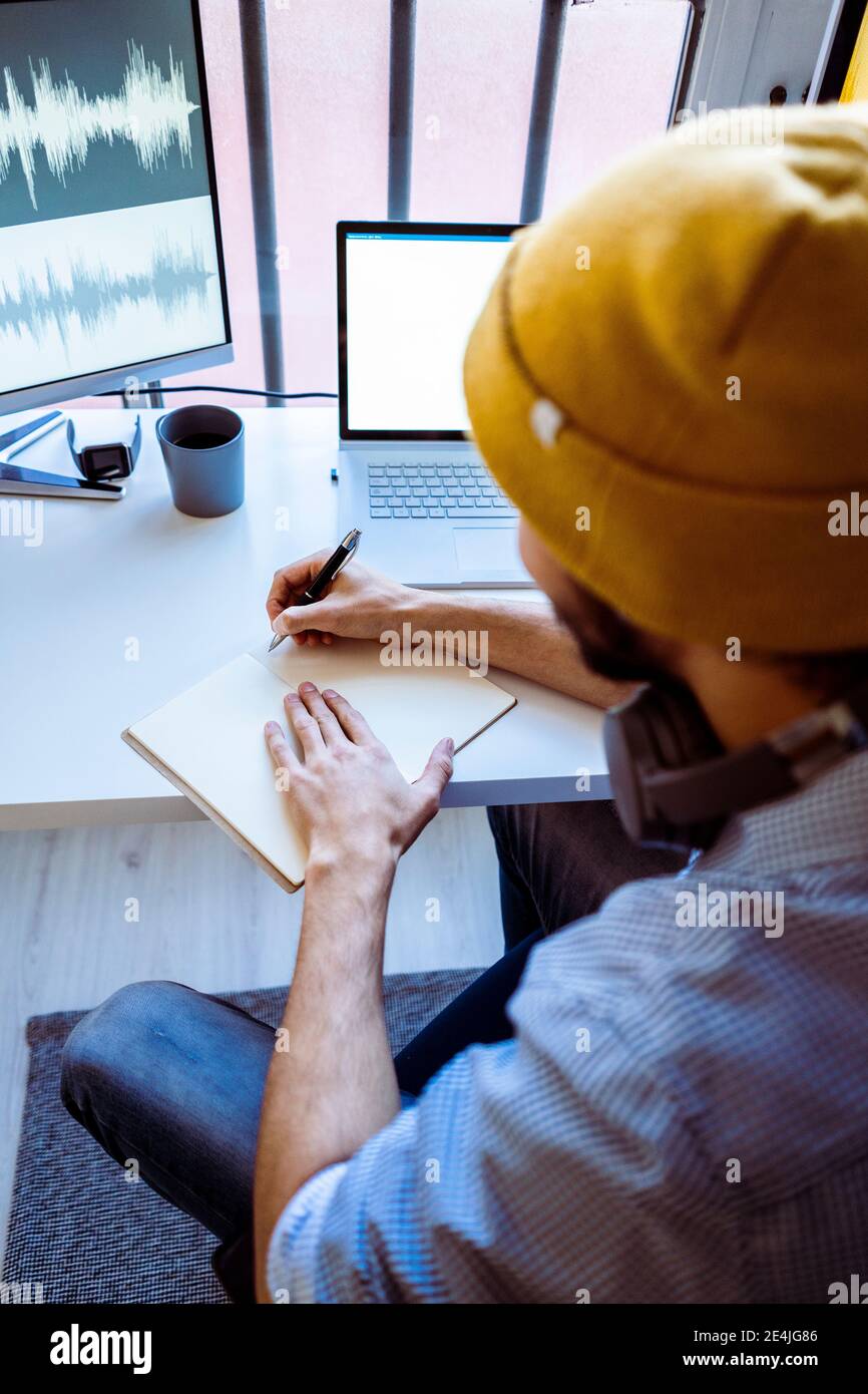 Male composer writing in book while sitting at studio Stock Photo