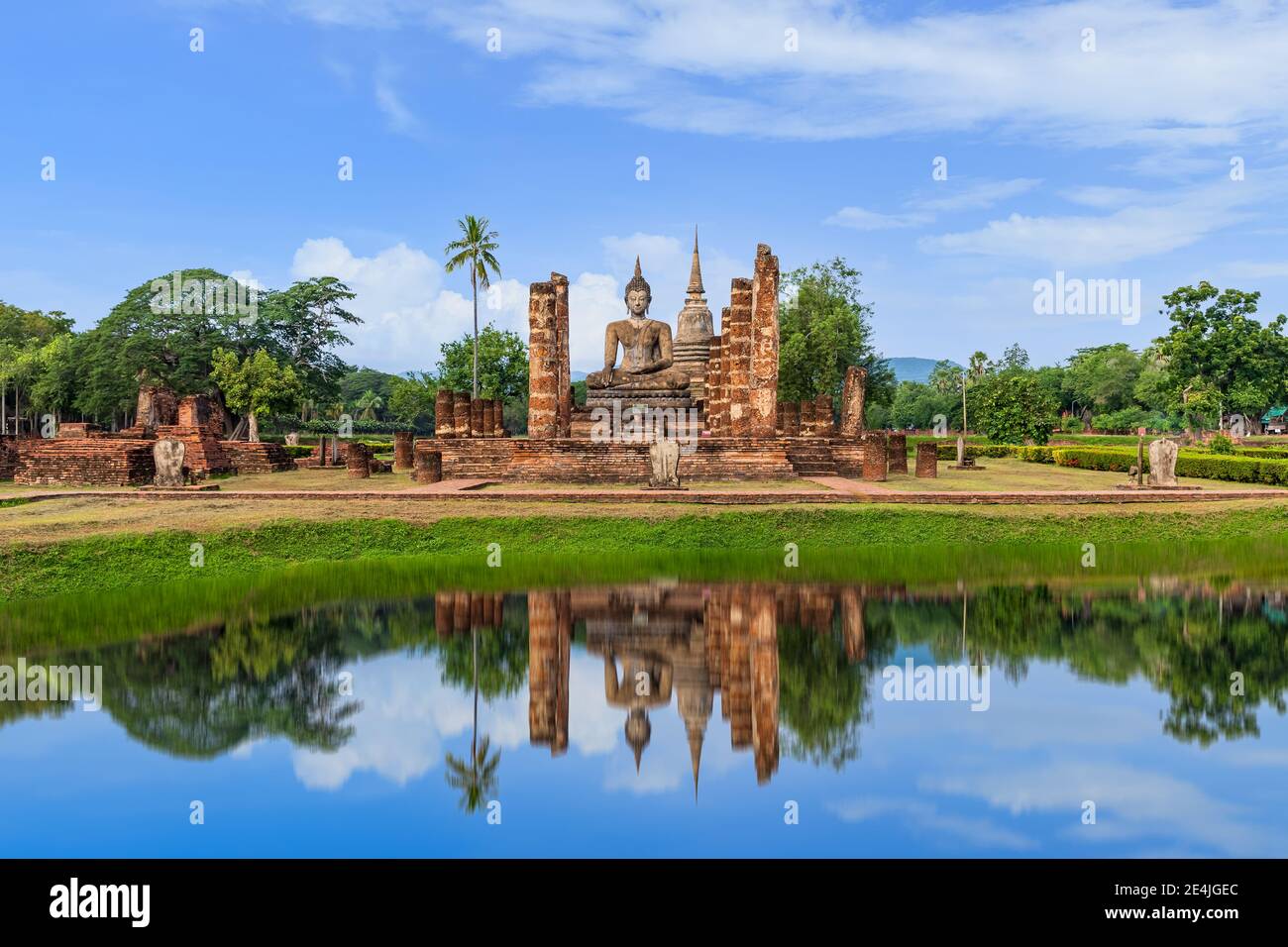 Buddha statue and Pagoda in ruined monastery complex at Wat Mahathat temple with reflection, Sukhothai Historical Park, Thailand Stock Photo