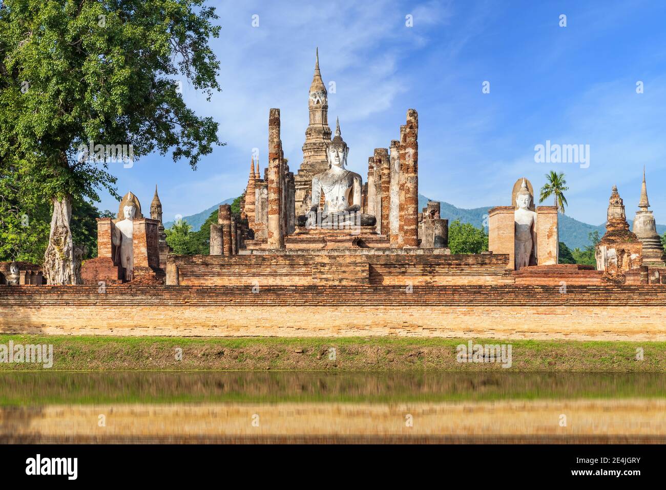 Buddha statue and Pagoda in ruined monastery complex at Wat Mahathat temple with reflection, Sukhothai Historical Park, Thailand Stock Photo