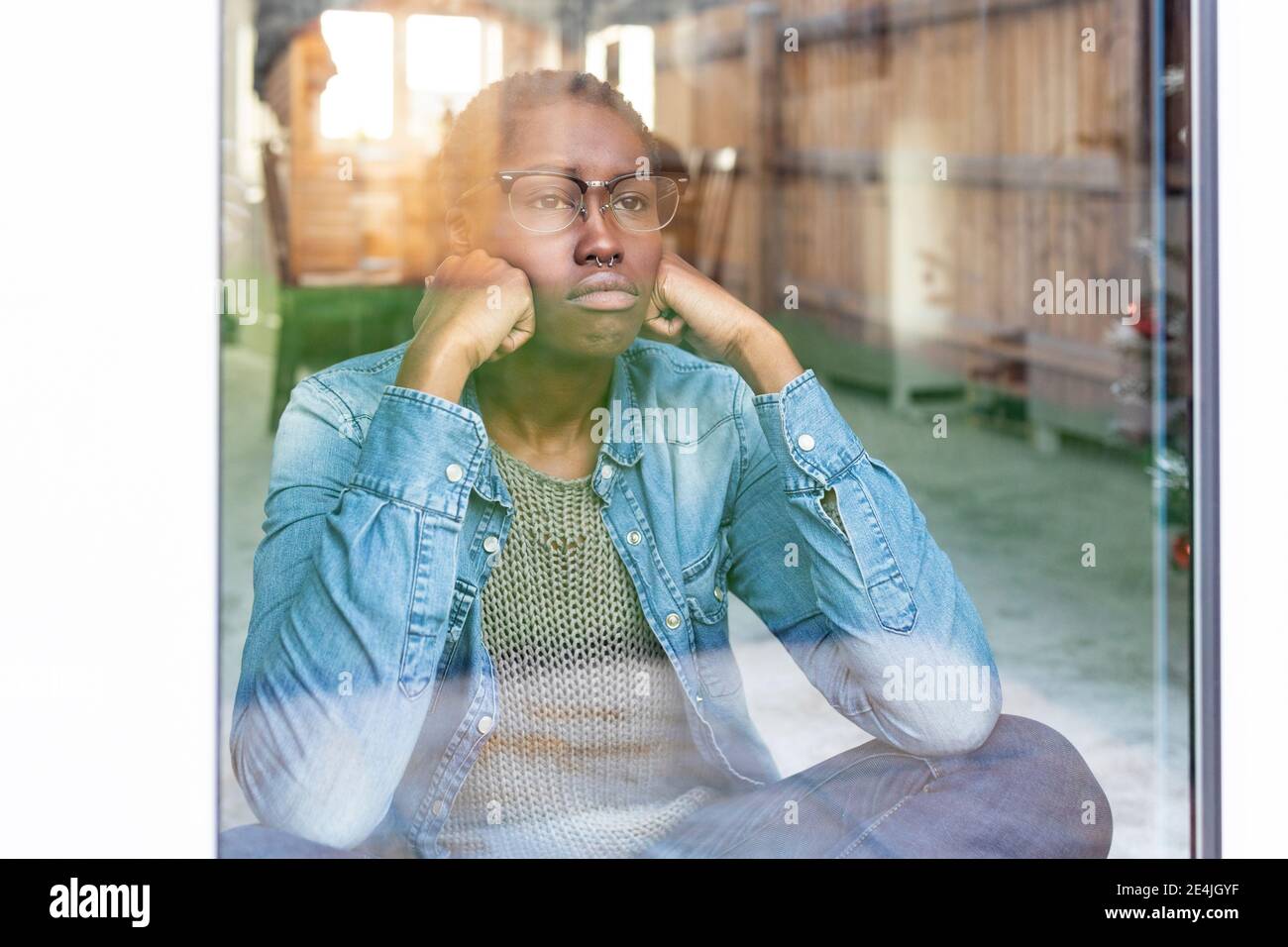 Sad woman looking through window Stock Photo