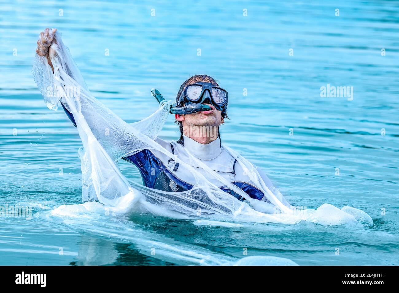Mature man wearing scuba mask tearing plastic in sea Stock Photo