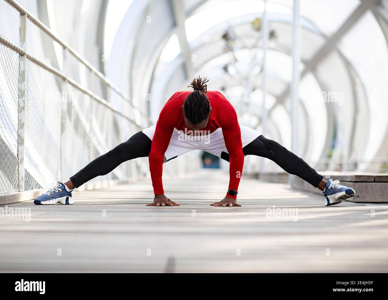 Male athlete practicing splits while exercising on walkway Stock Photo ...