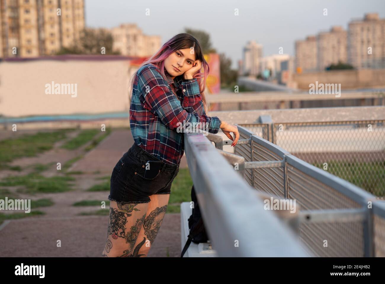 Hipster female with pink hair leaning on railing at rooftop Stock Photo
