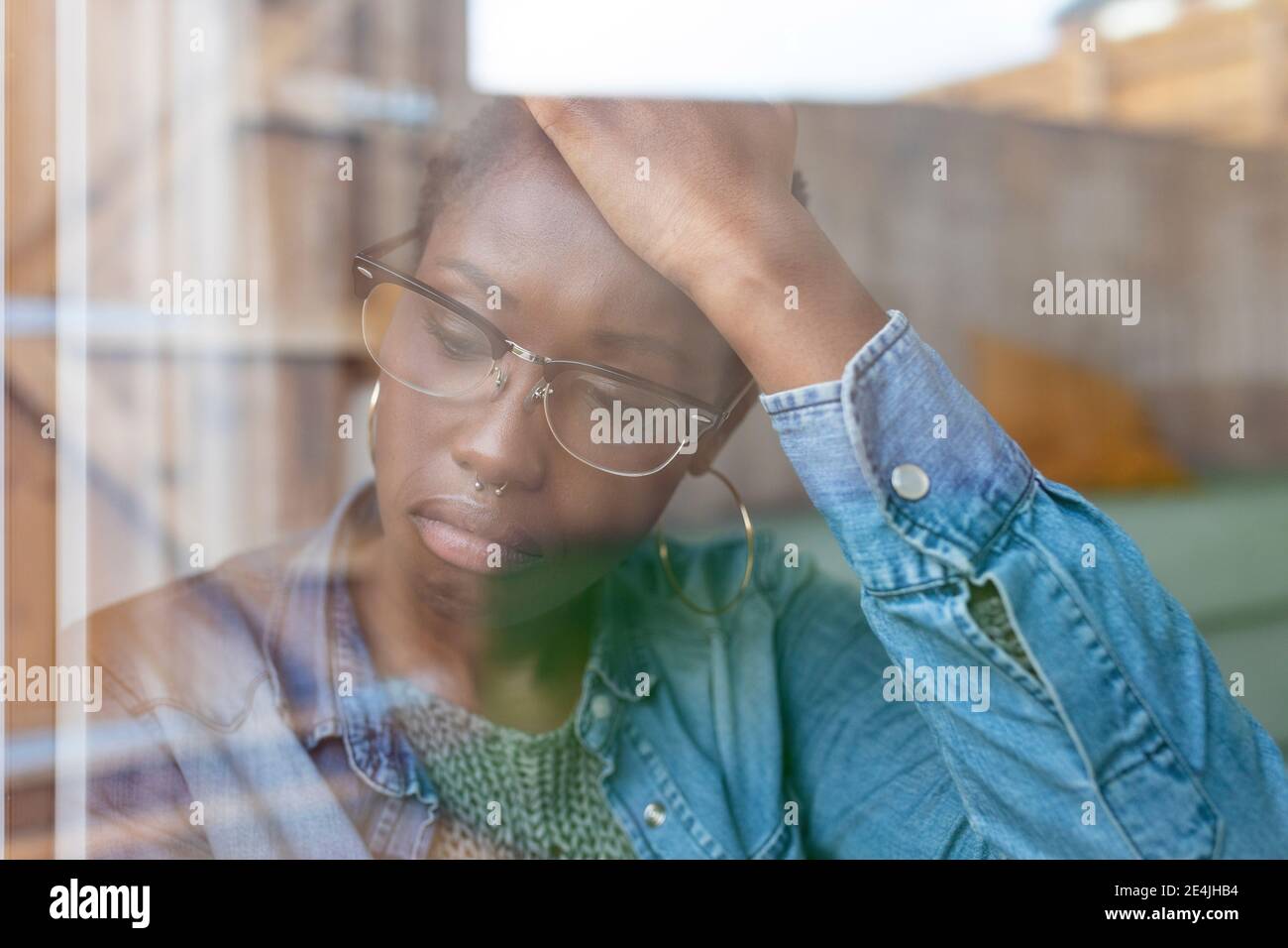 Sad woman looking through window Stock Photo