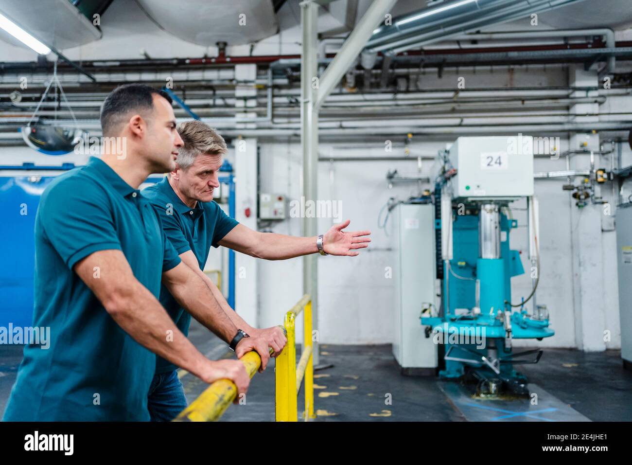 Male technicians discussing while working in factory Stock Photo
