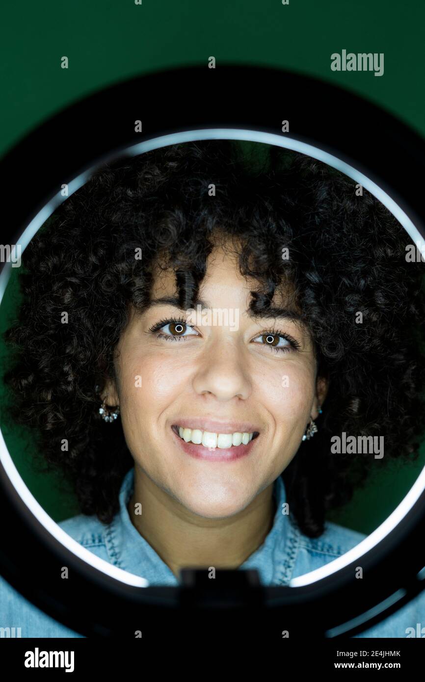 Portrait of young woman with dark brown curly hair reflecting in round mirror Stock Photo