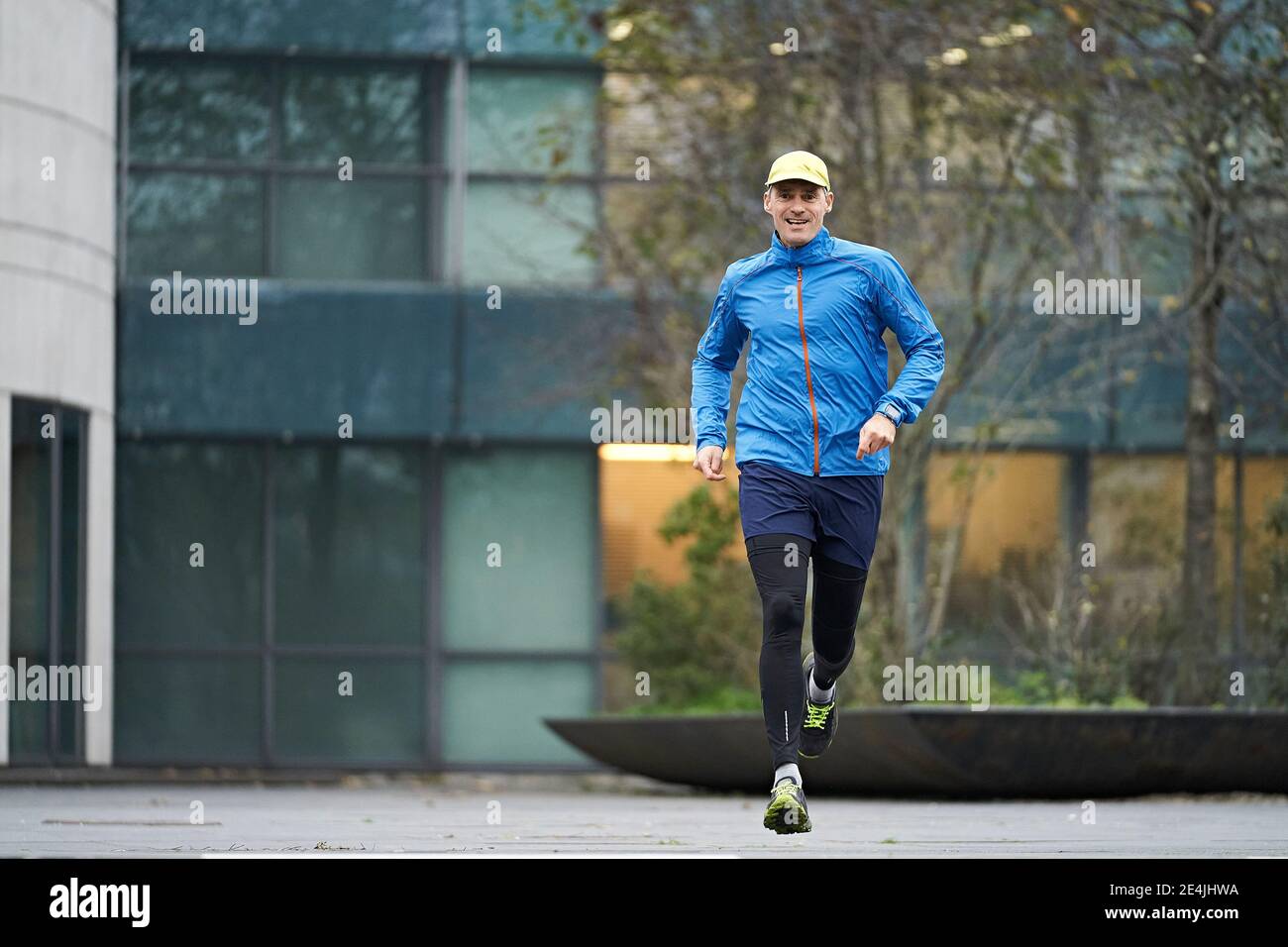 Mature man jogging wearing cap against building Stock Photo