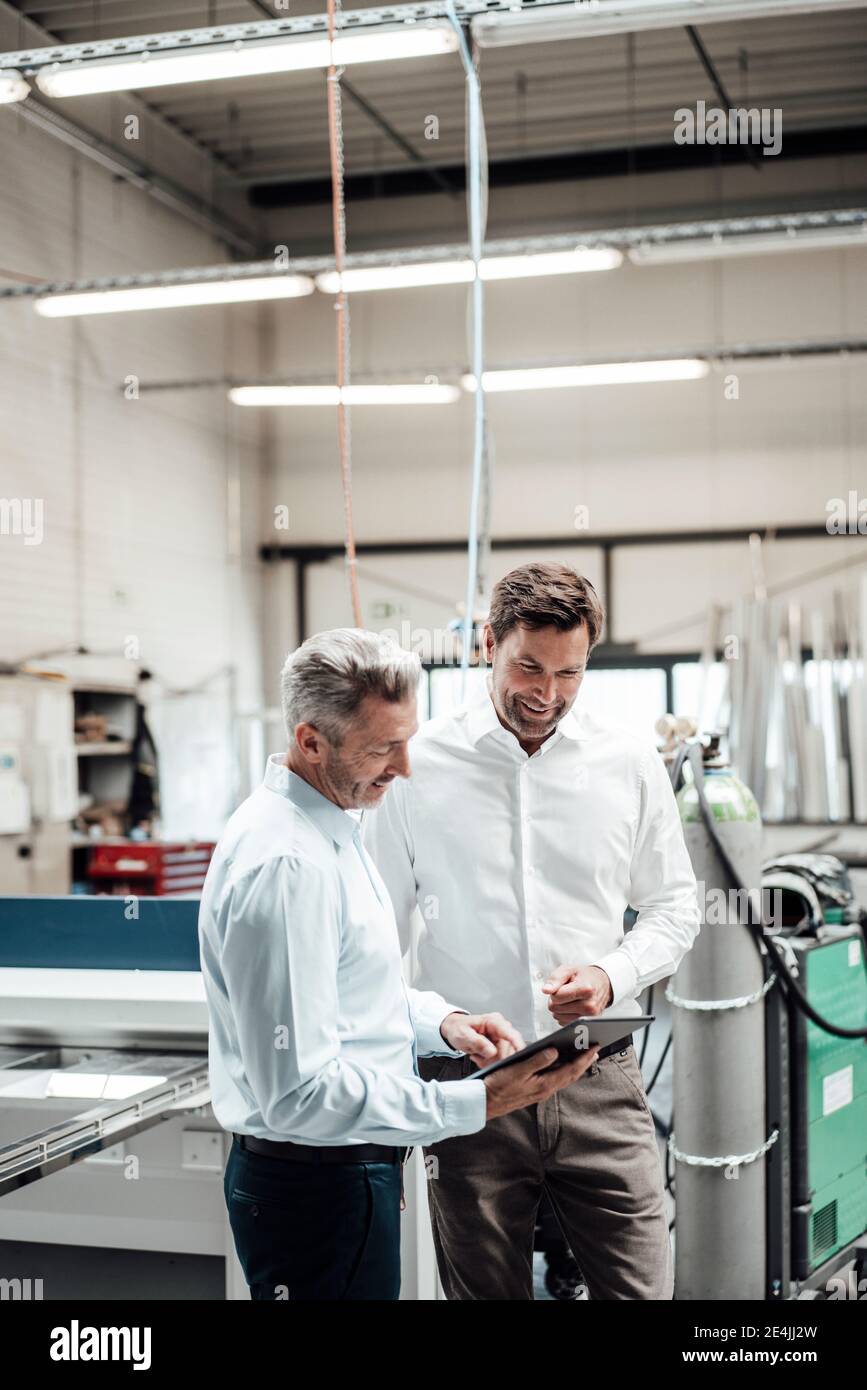 Professionals using digital tablet while working at industry Stock Photo