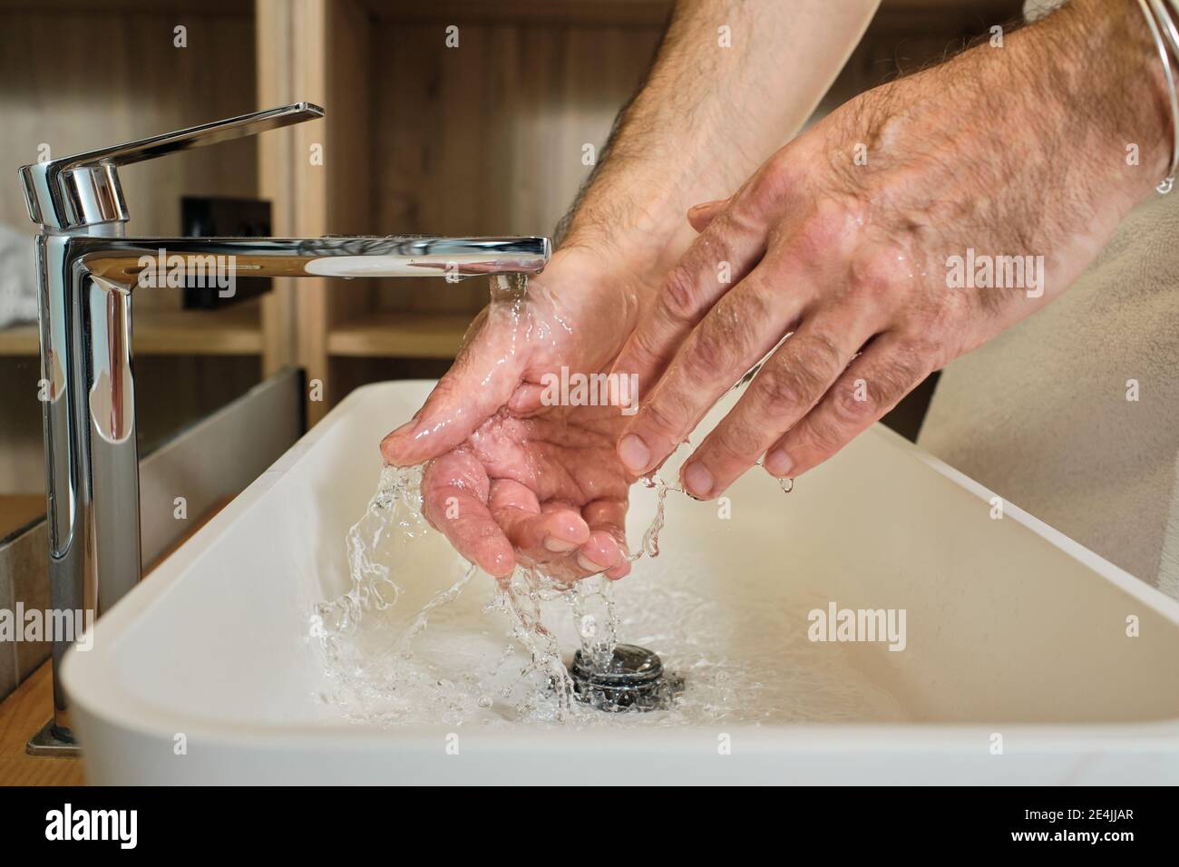 Mature man washing hands in running water in bathroom at home Stock Photo