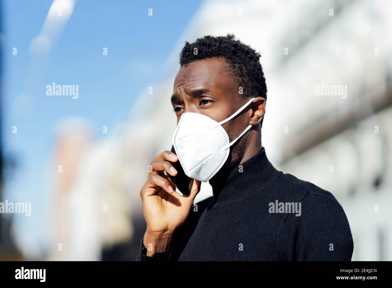 Young man talking on mobile phone while standing outdoors Stock Photo