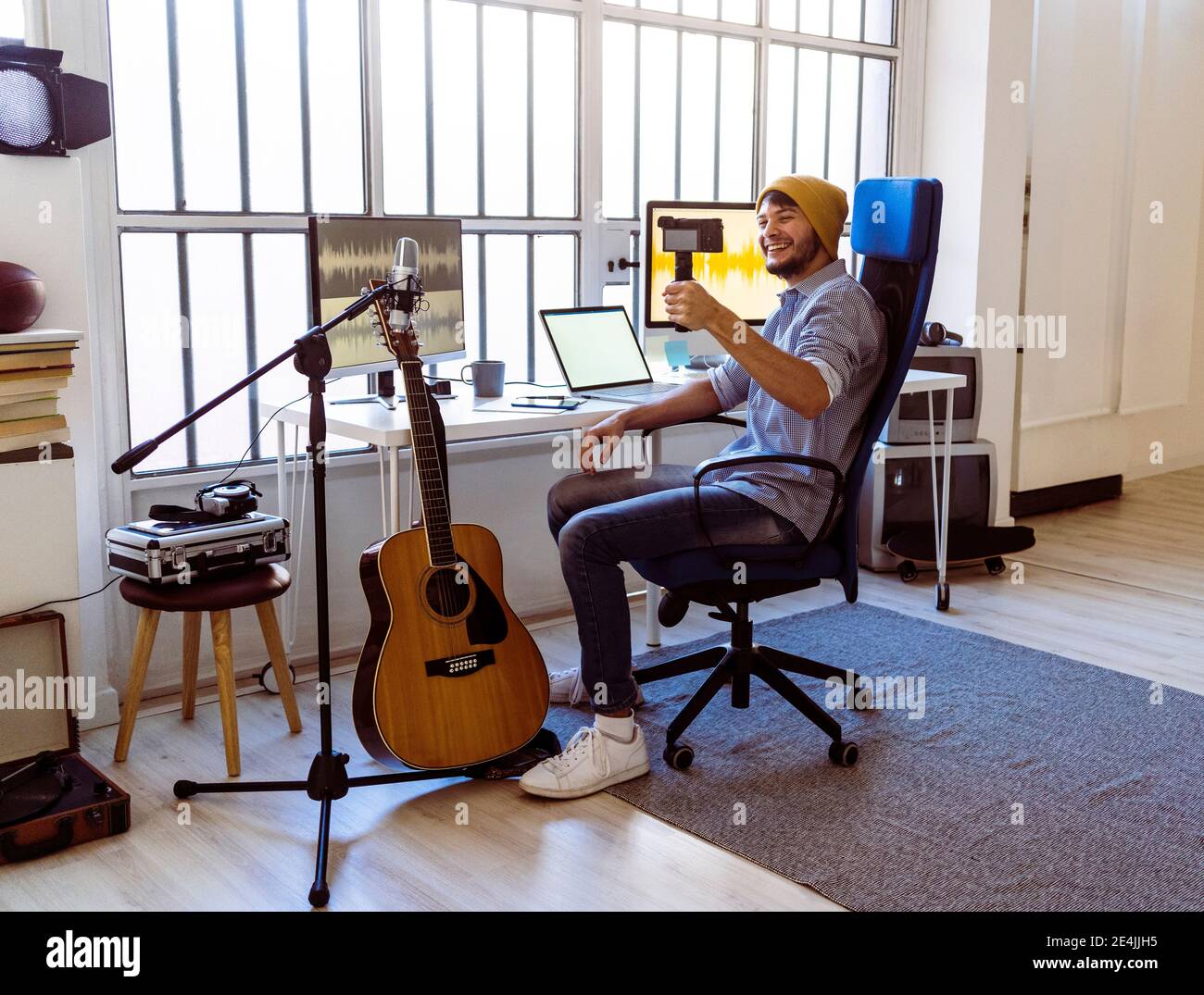 Musician making vlog while sitting at studio Stock Photo