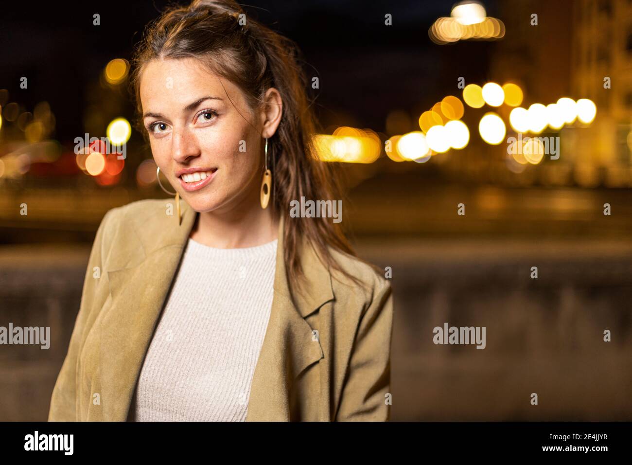 Young woman smiling while standing outdoors Stock Photo