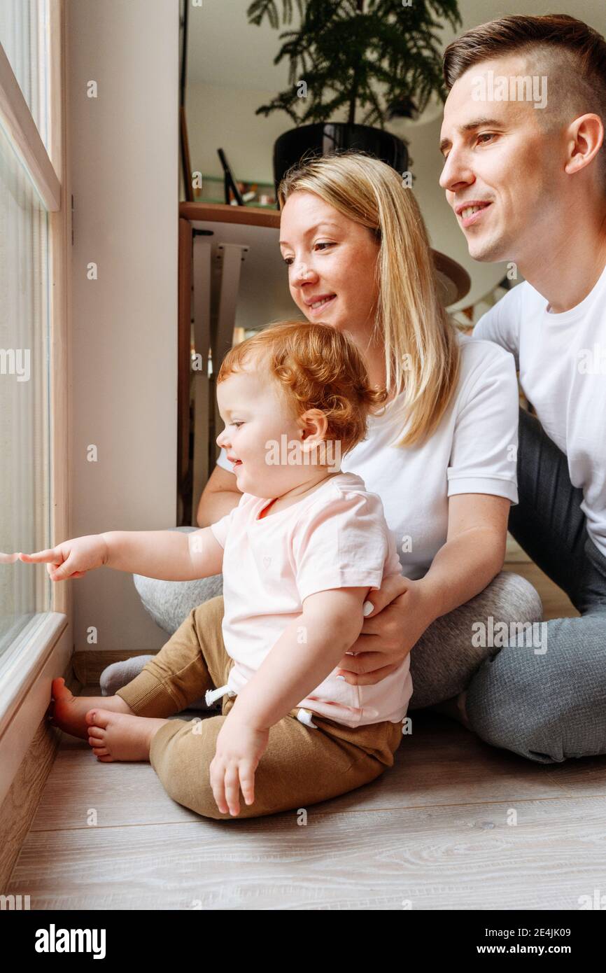 Happy family with baby daughter looking through window Stock Photo