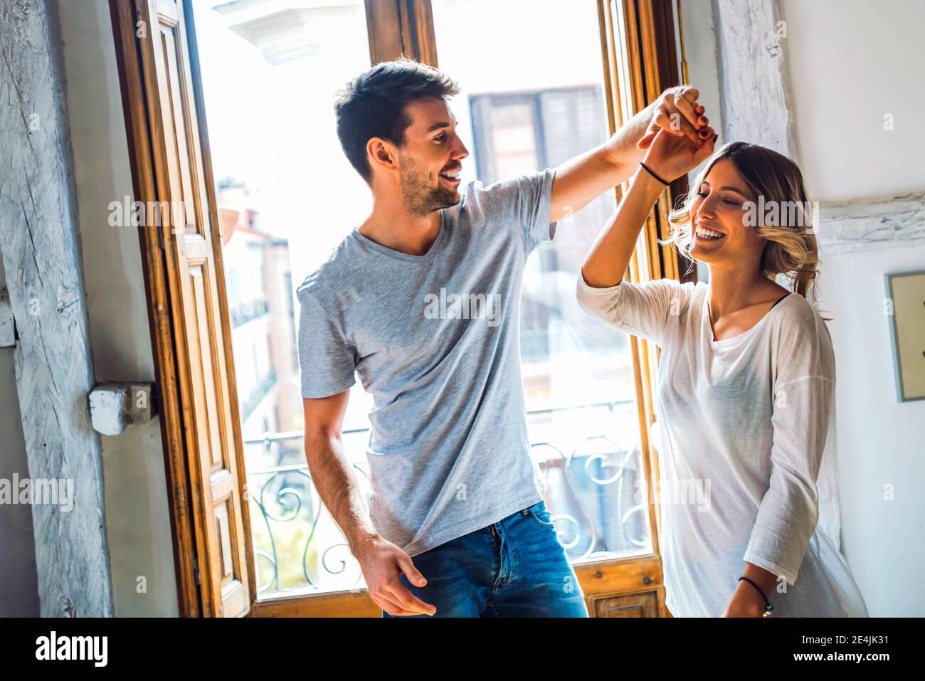 Happy young couple dancing at the window at home Stock Photo