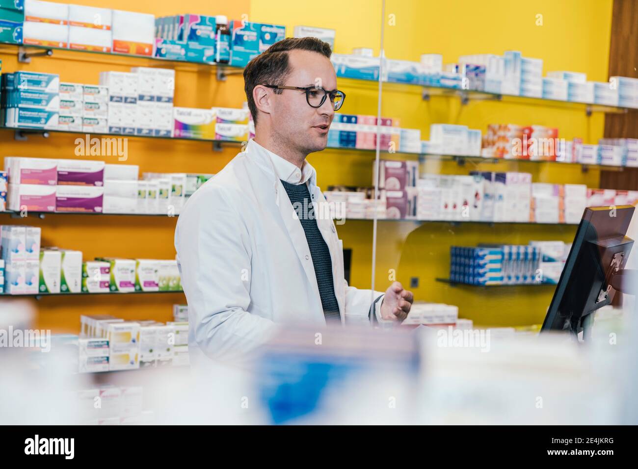 Pharmacist wearing lab coat while working in chemist shop Stock Photo