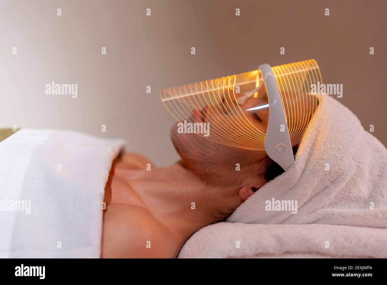 Young woman wearing mask during rejuvenating treatment at beauty spa Stock Photo