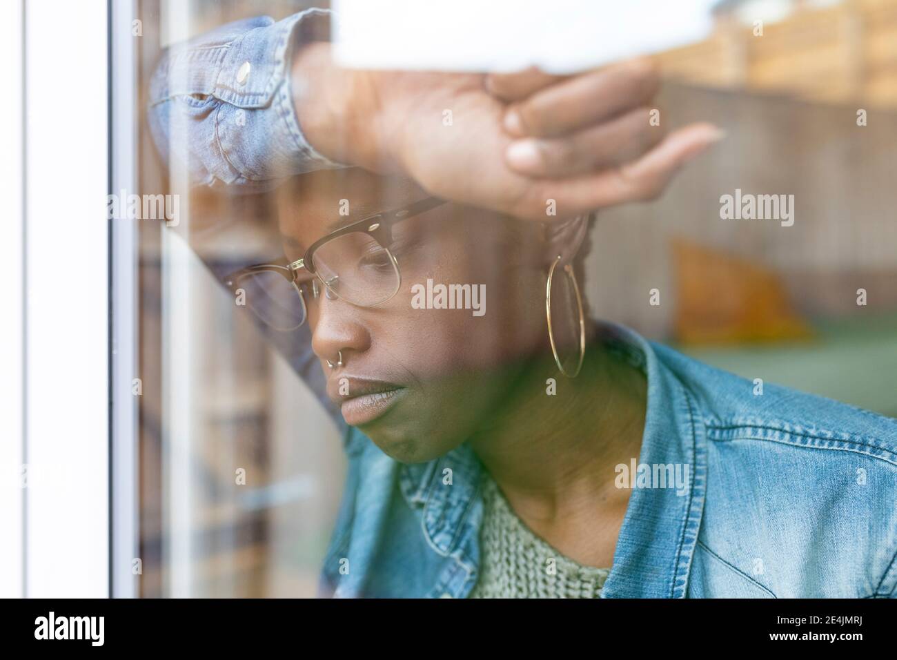 Sad woman looking through window Stock Photo