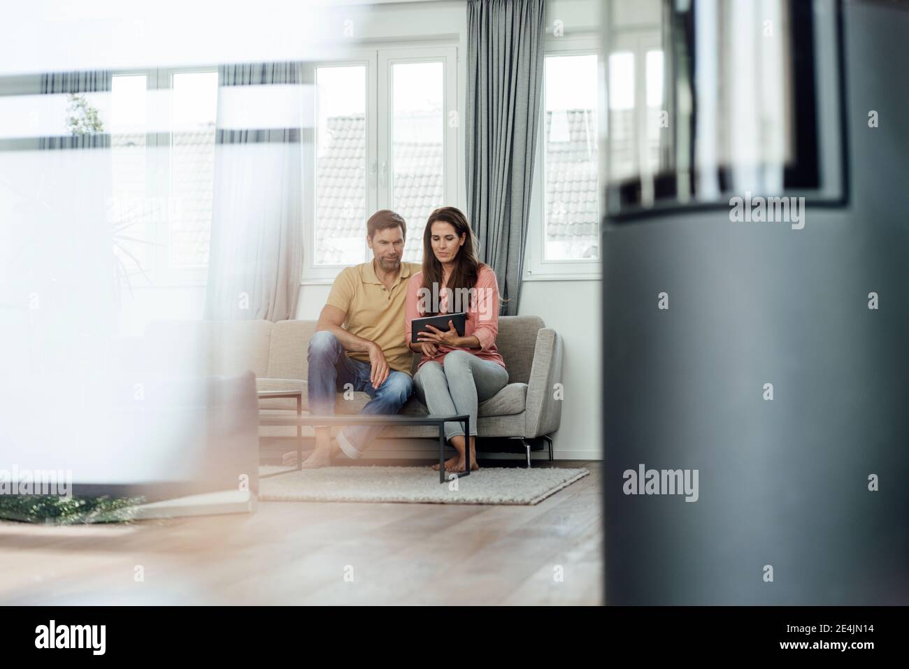 Mature couple using digital table while sitting on sofa in apartment Stock Photo
