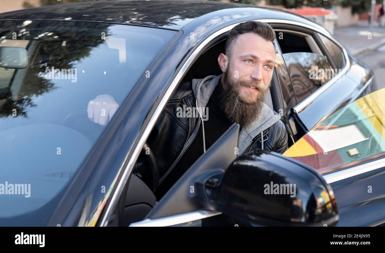 Bearded man disembarking from car Stock Photo