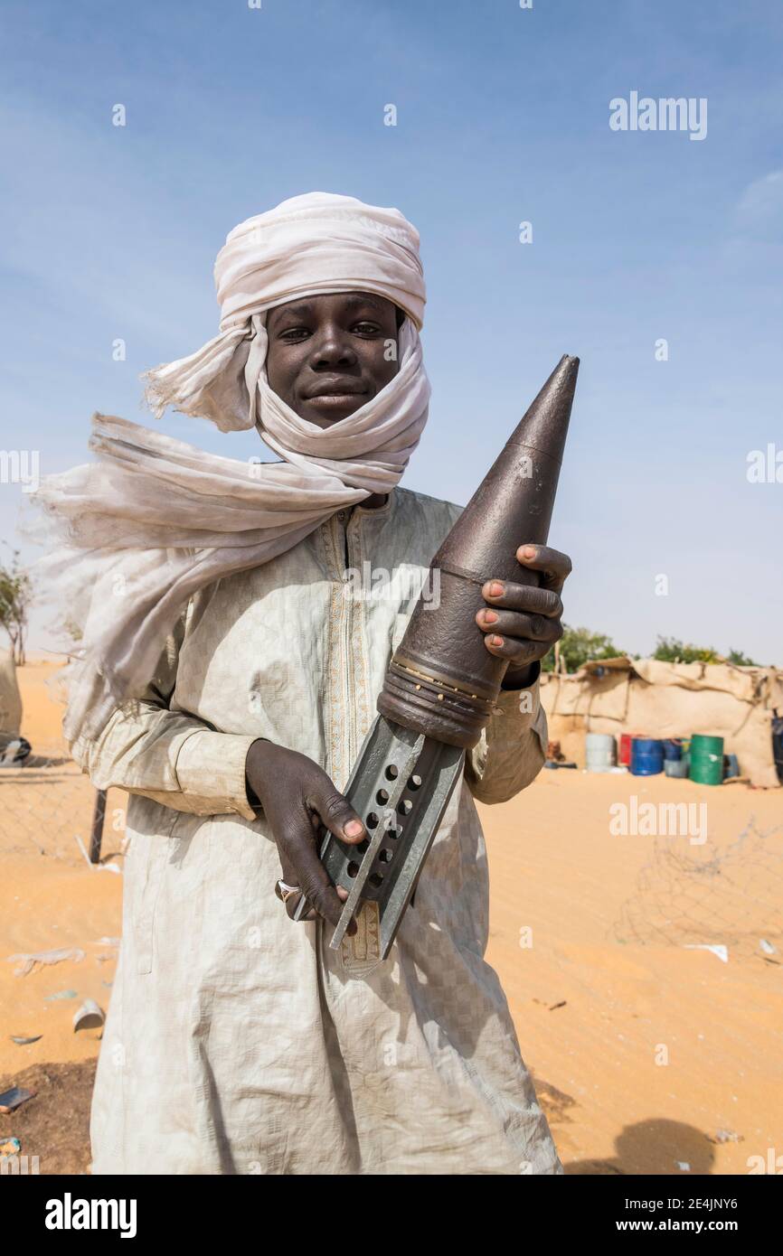 Young Man posing with an old rockethead, between Faya-Largeaux and N'Djamena, Sahara, Chad Stock Photo