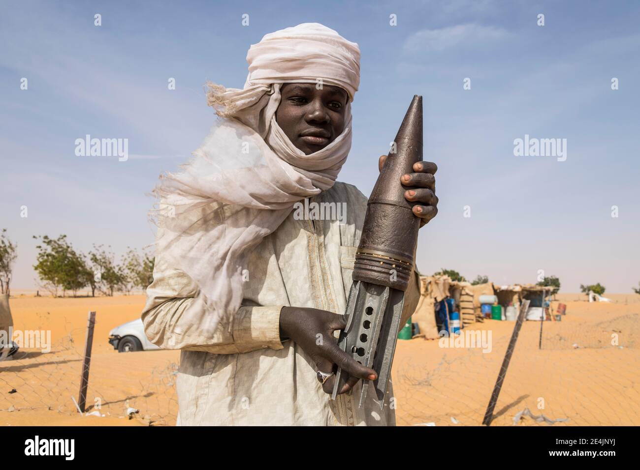 Young Man posing with an old rockethead, between Faya-Largeaux and N'Djamena, Sahara, Chad Stock Photo
