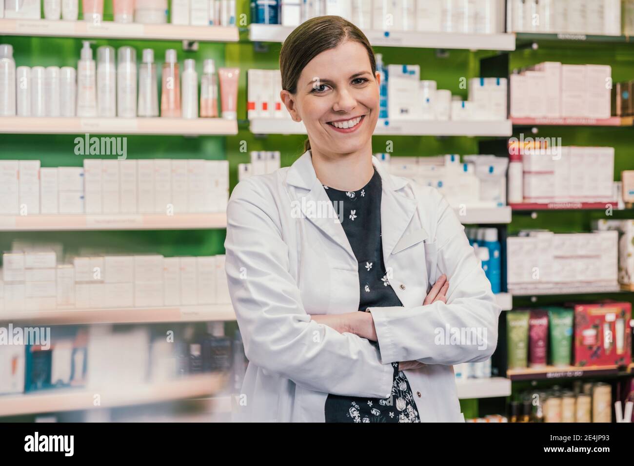 Smiling pharmacist with arms crossed in chemist shop Stock Photo