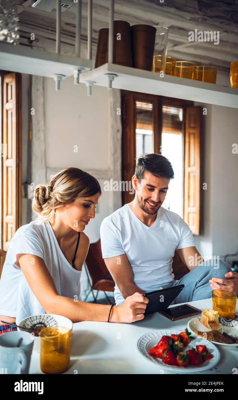 Young couple watching tablet while having breakfast at home Stock Photo
