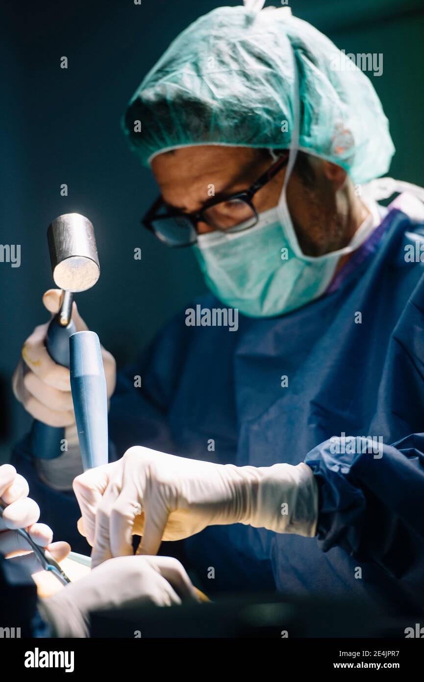 Male orthopedic surgeons using medical equipment for ankle surgery in operating room Stock Photo