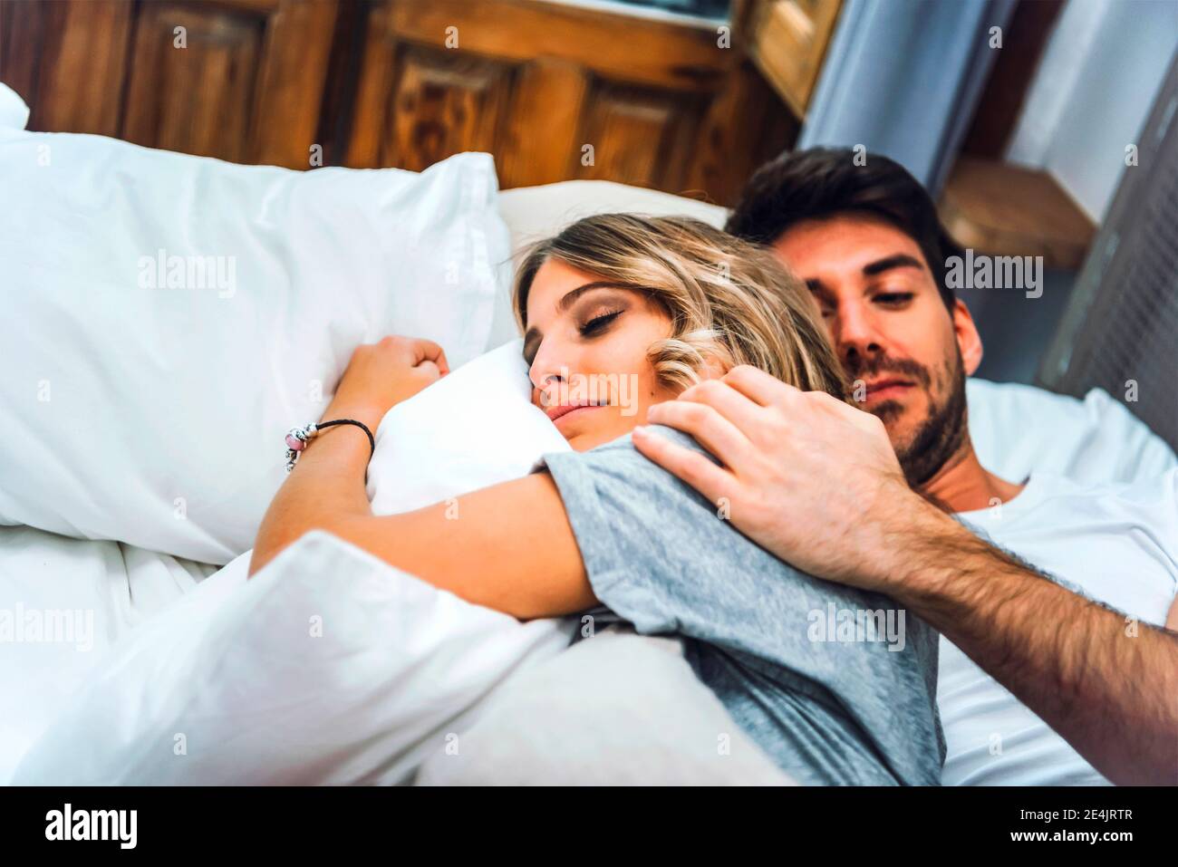 Affectionate young couple lying in bed at home Stock Photo