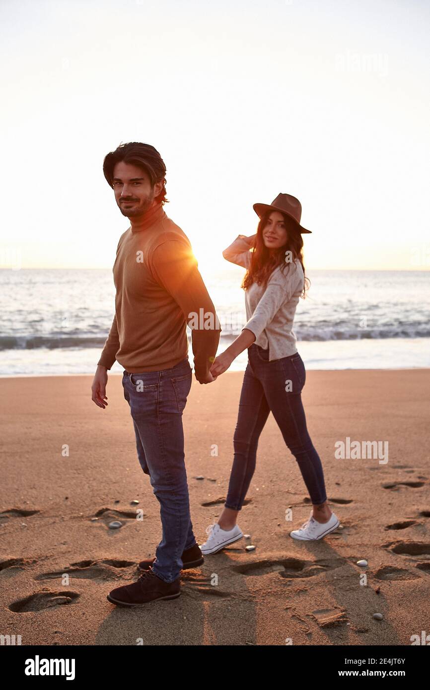Young couple holding hands while walking on beach Stock Photo