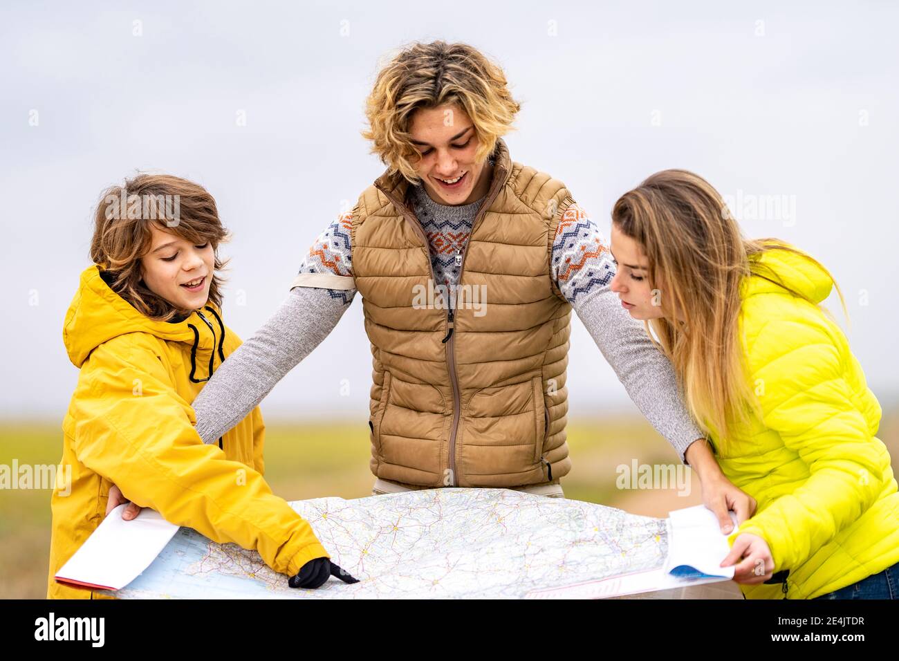 Three siblings checking map during hike Stock Photo