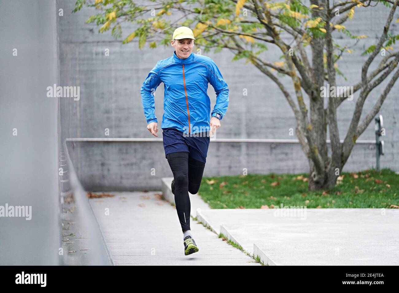 Mature man wearing cap jogging on footpath Stock Photo