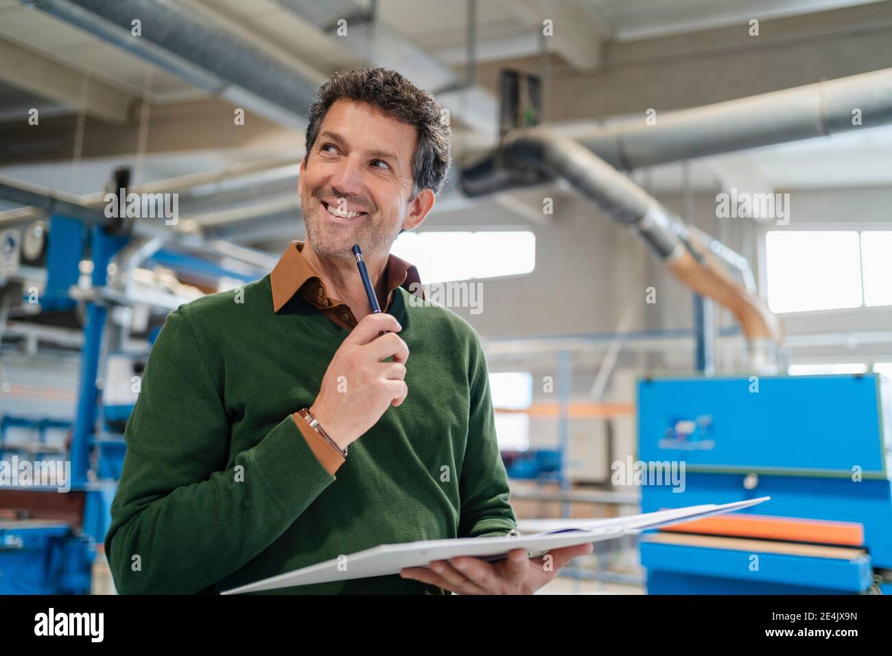Portrait of carpenter smiling with ring binder in hands Stock Photo