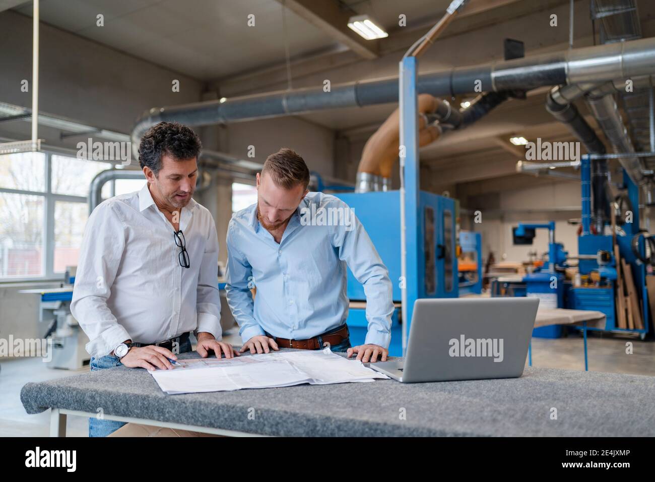 Two carpenters talking over documents in production hall Stock Photo