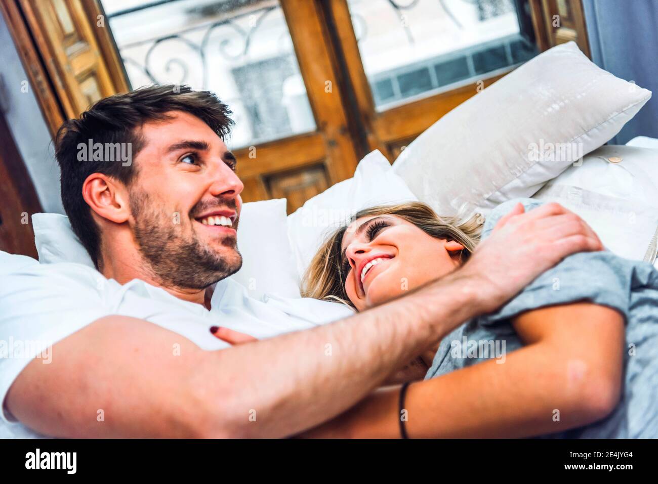 Happy affectionate young couple lying in bed at home Stock Photo