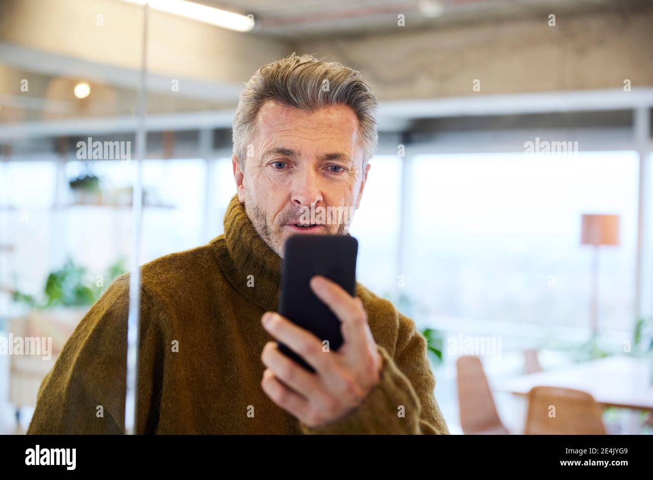 Surprised man looking at mobile phone at home Stock Photo