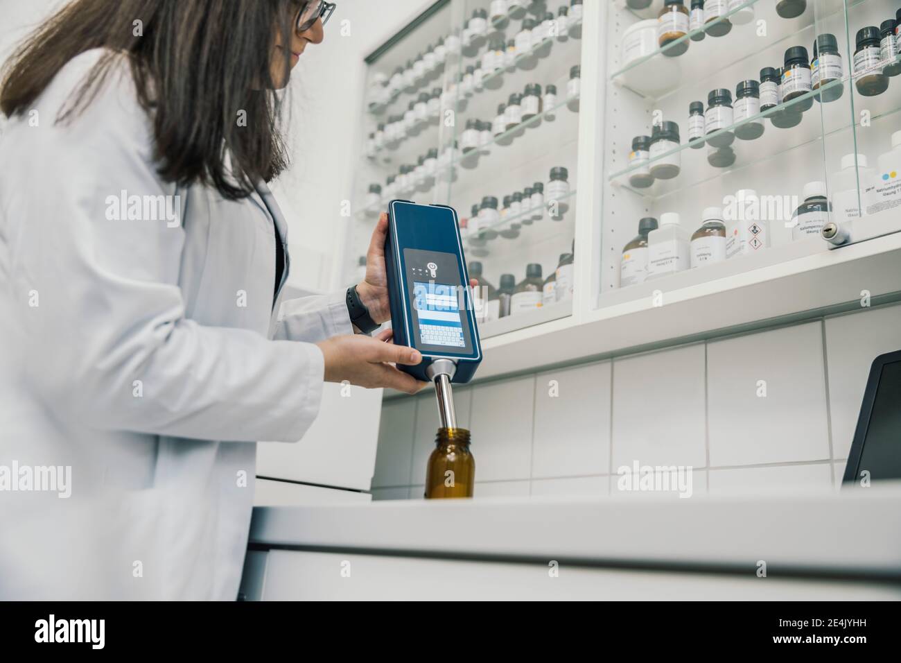 Midsection of female pharmacist using NIR spectrometer in chemist store Stock Photo