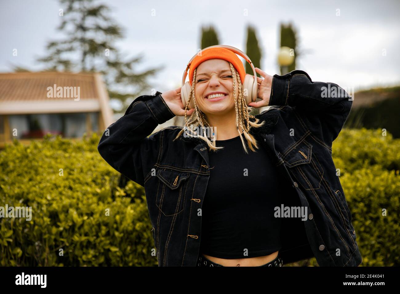 Happy woman in jacket with eyes close listening music through headphones Stock Photo