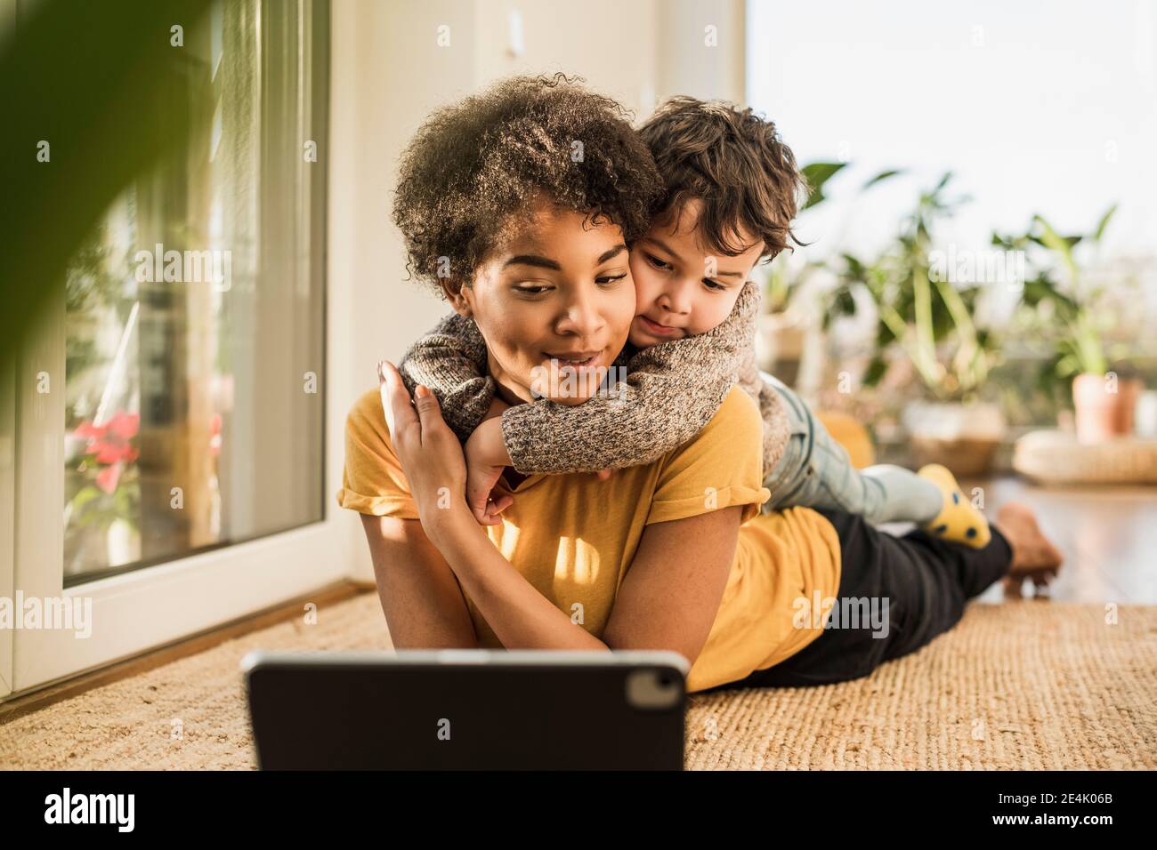 Mother and son using digital tablet while lying at home Stock Photo