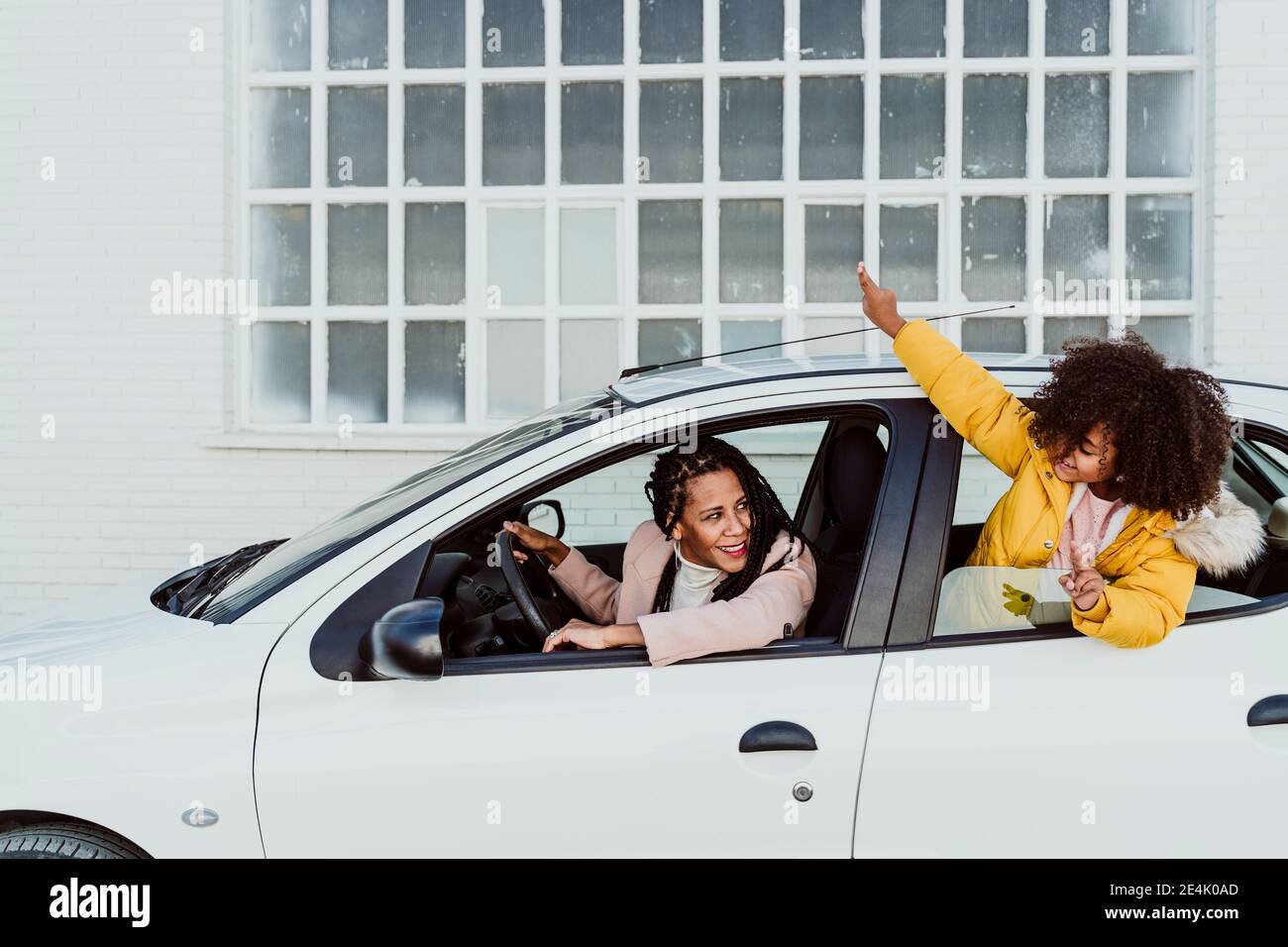 Smiling mother looking at daughter peeking through window in car Stock Photo