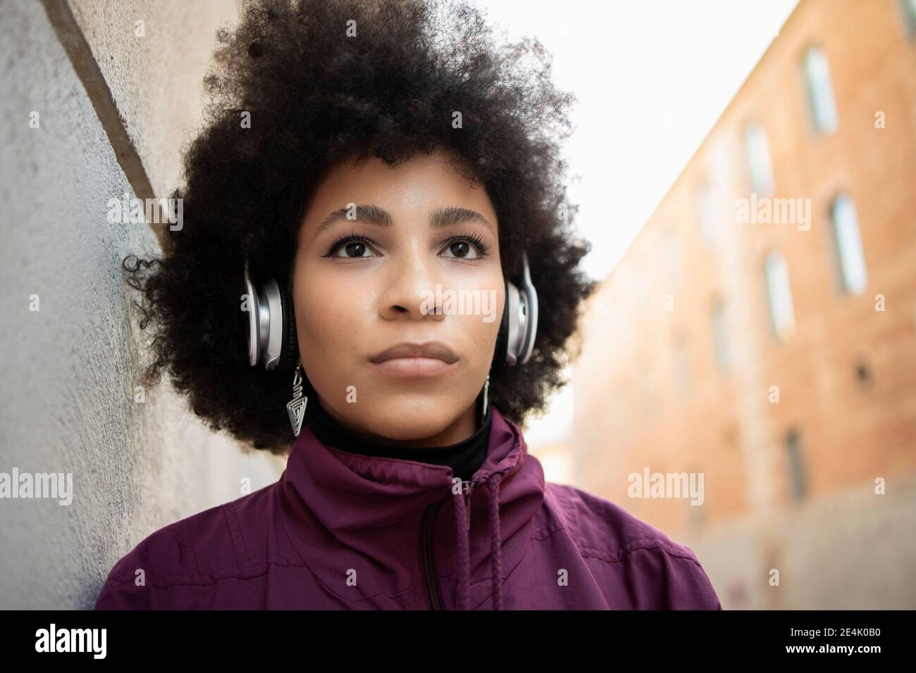 Cheerful woman wearing headphones against built structure Stock Photo
