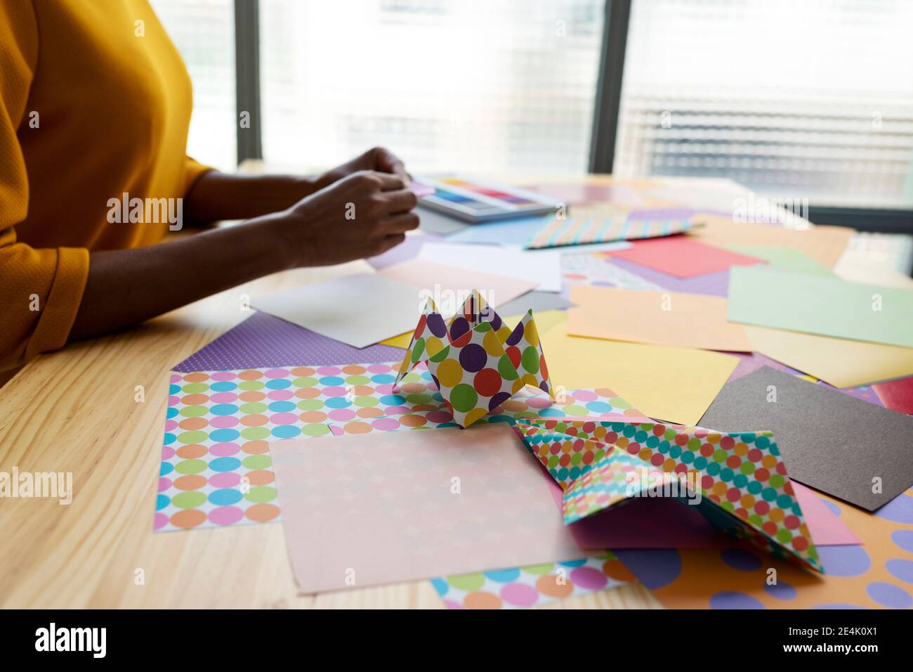 Origami artist sitting in studio folding colorful paper Stock Photo