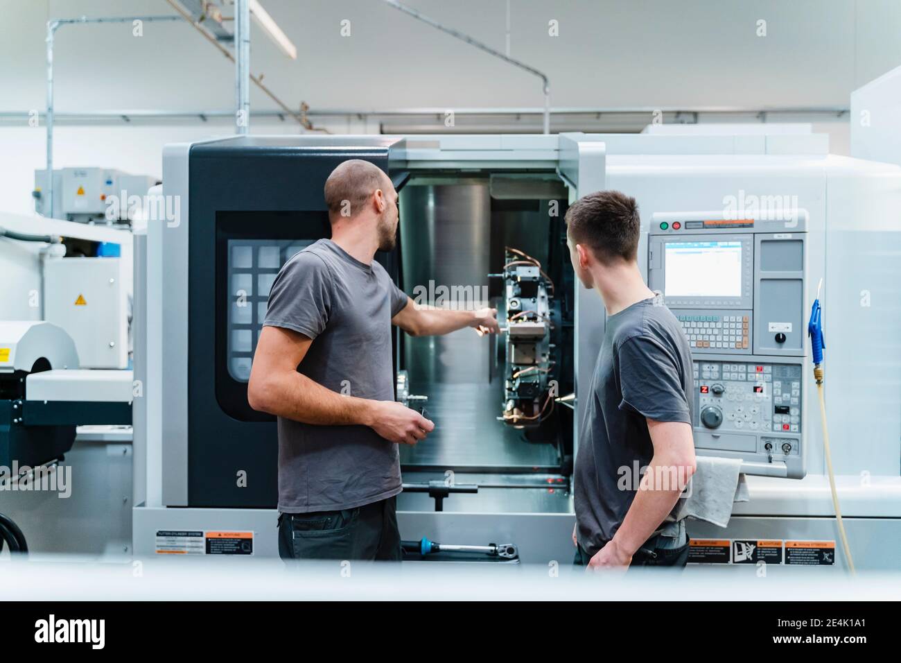 Engineer showing machine part to trainee while working at industry Stock Photo